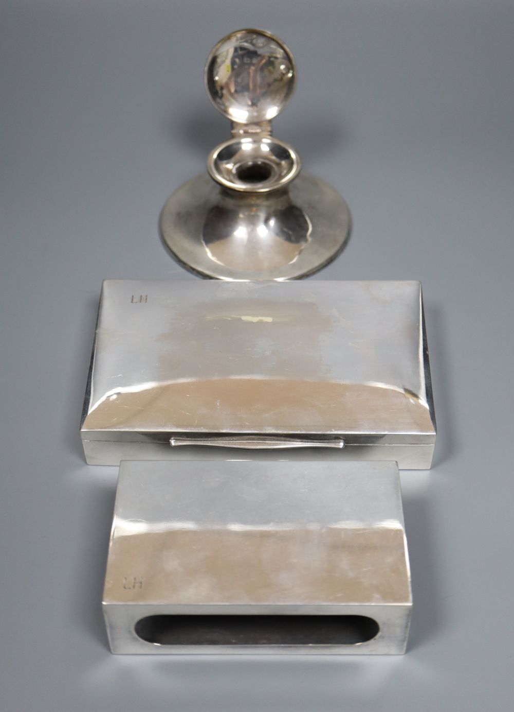 An 800 standard matchbox holder, and cigarette box and a silver capstan inkwell.